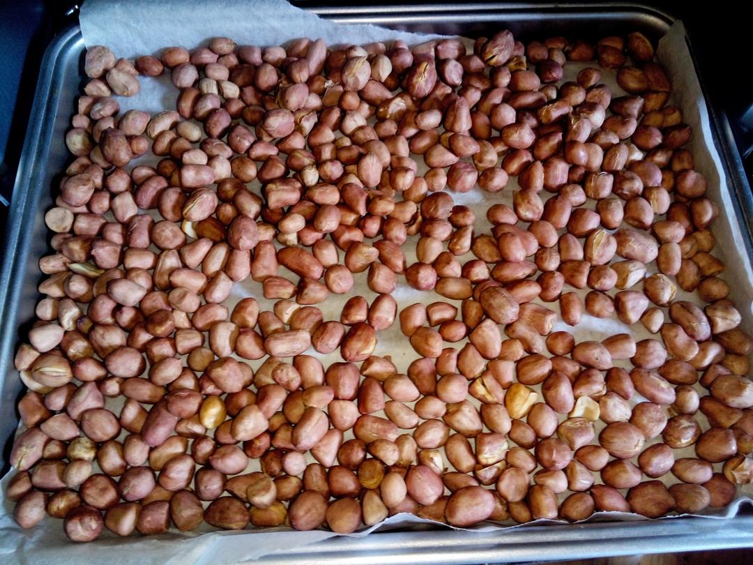 图示:预热中的嵌入式烤箱,显示屏温度140℃;烤盘上单层铺放浅米色花生仁,间隔清晰;右下角红外测温枪对准仁体,读数82℃;旁置小碗盛放已烘好冷却的花生,红衣自然卷曲散落于盘底 烤箱干烘法流程图