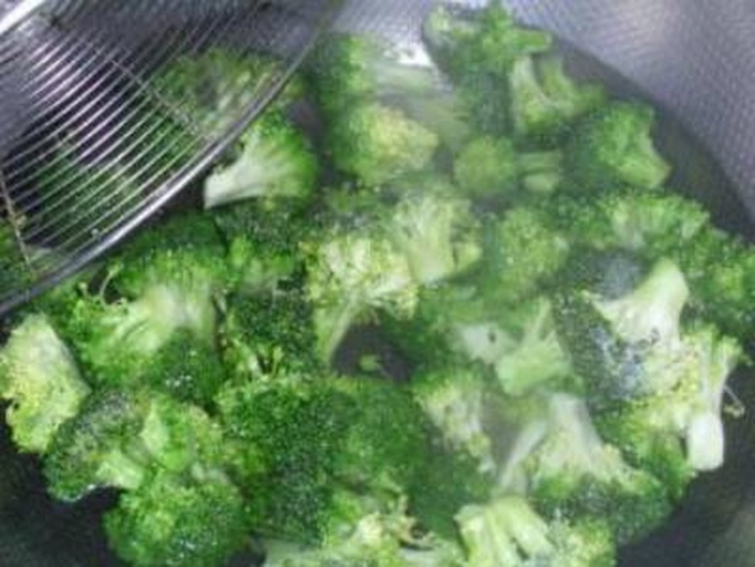 纪实摄影:家庭厨房中标准化西兰花焯烫操作过程,强调时间精准控制(60秒)与温度管理(微温拌制),体现科学膳食的可复制性 家庭厨房操作场景:手部特写正将焯烫60秒的西兰花小朵倒入滤盆沥水,背景可见计时器显示01:00,案板上摆放泡发好的毛木耳与玻璃碗