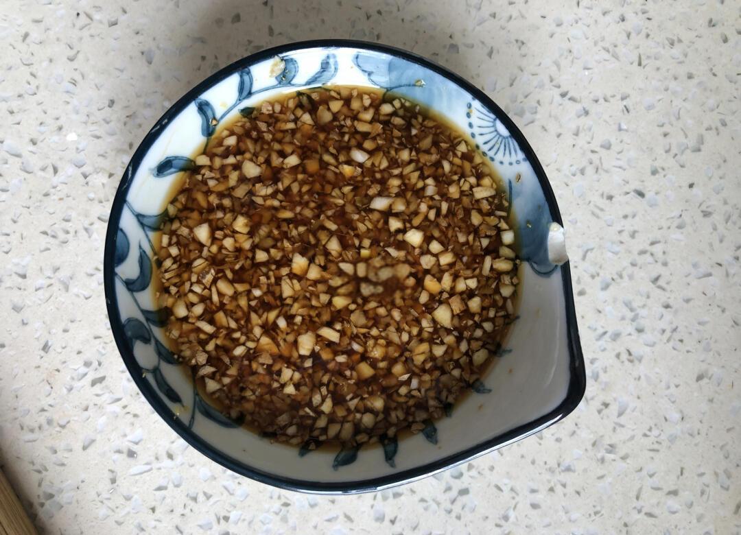 砧板上摆放两个小碟，左碟为极细蒜末，右碟为略粗的蒜粒，旁边有半颗剥好的大蒜和一把厨师刀