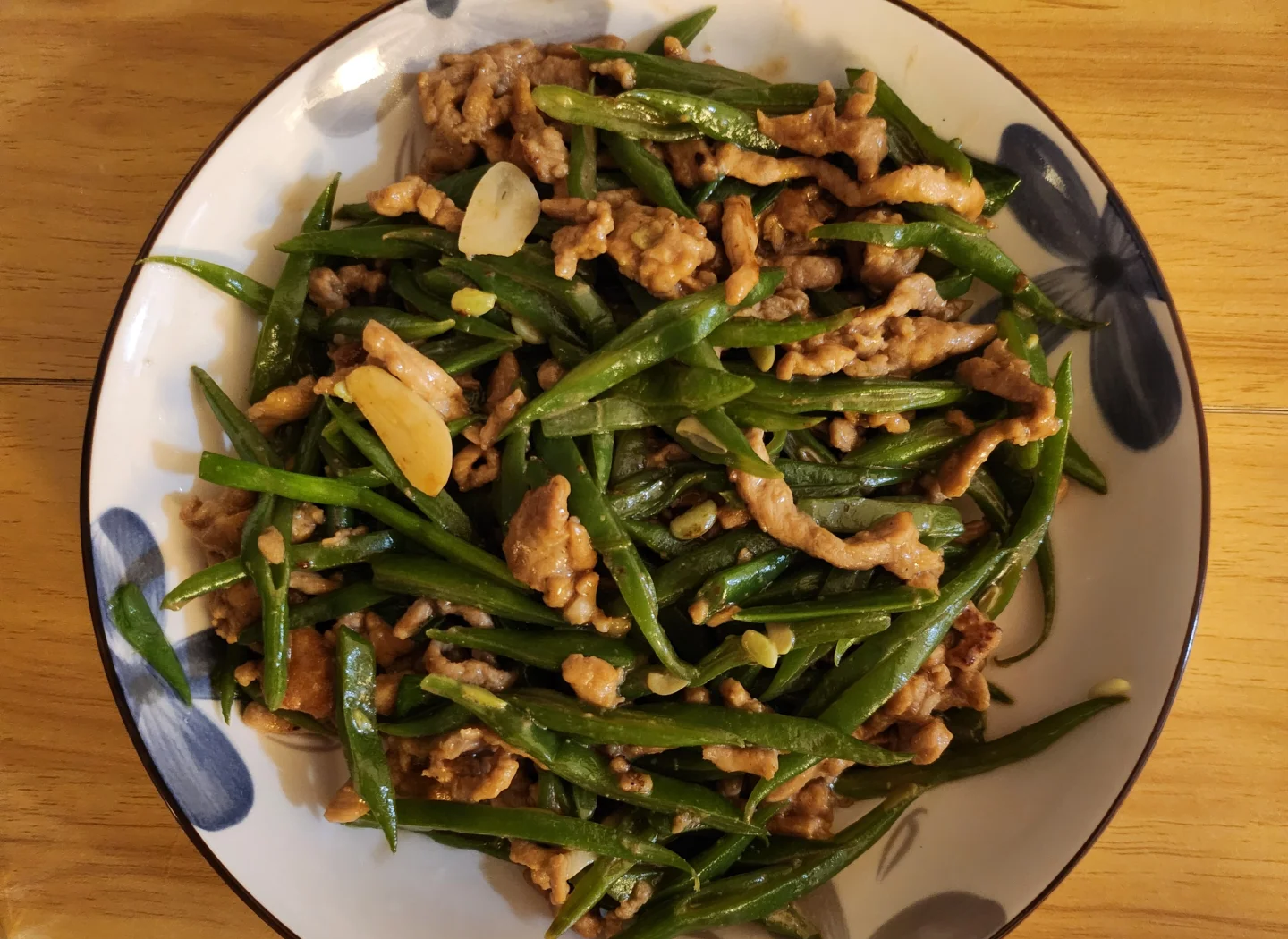 专业厨房实拍:中餐爆炒四季豆过程,锅气十足,豆荚形态完整无软烂,佐料简洁(蒜末、红椒),突出‘短时高温’核心工艺 厨房场景:不锈钢炒锅中四季豆正在快炒,豆荚呈鲜亮翠绿色,油光均匀,辅以蒜末与红椒丝,火苗旺盛,体现“急火快炒”工艺要点