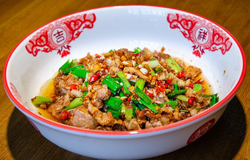 厨师正在灶台前翻炒一锅青翠欲滴的陇椒