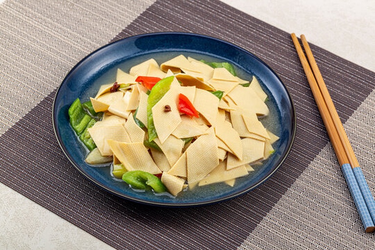 一张木制餐桌上摆放三道豆筋子菜肴:酱烧豆筋子(红亮浓郁)、凉拌豆筋子(青红搭配清爽)、火锅涮豆筋子(夹在筷子上滴着汤汁),背景为家庭聚餐氛围,体现美食实用性 豆筋子家常菜肴拼盘
