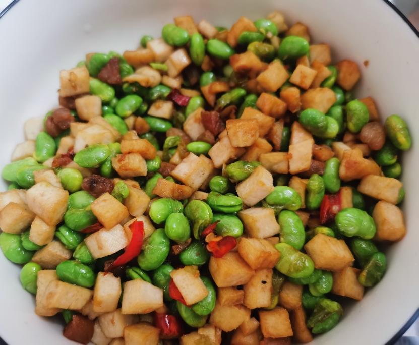 煮熟的淡绿色毛豆仁摆放在白色瓷碗中