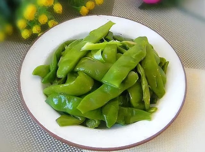 一盘色香味俱全的芥兰炒荷兰豆成品,盛放在白色盘中,色泽鲜亮,香气扑鼻 芥兰炒荷兰豆成品展示
