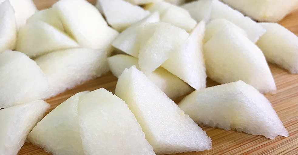 一位经验丰富的木雕工匠坐在工作台前,手持刻刀正在精心雕琢一块浅黄色的南果梨木,木屑微扬,半成品呈现出细腻的花纹,背景摆放着已完成的木艺作品 工匠正在手工雕刻一块南果梨木原料