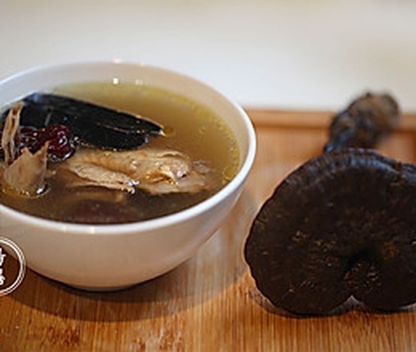 成品黑灵芝煲鸡汤盛入瓷碗特写