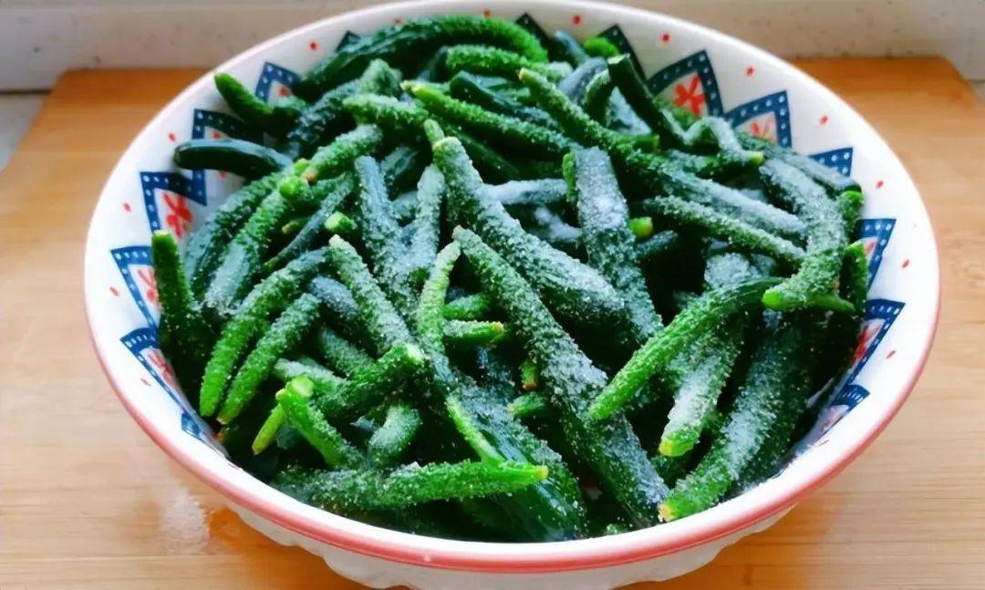 餐桌上摆着一碗腌小黄瓜，旁边是白粥、馒头和煎蛋，呈现家常早餐场景