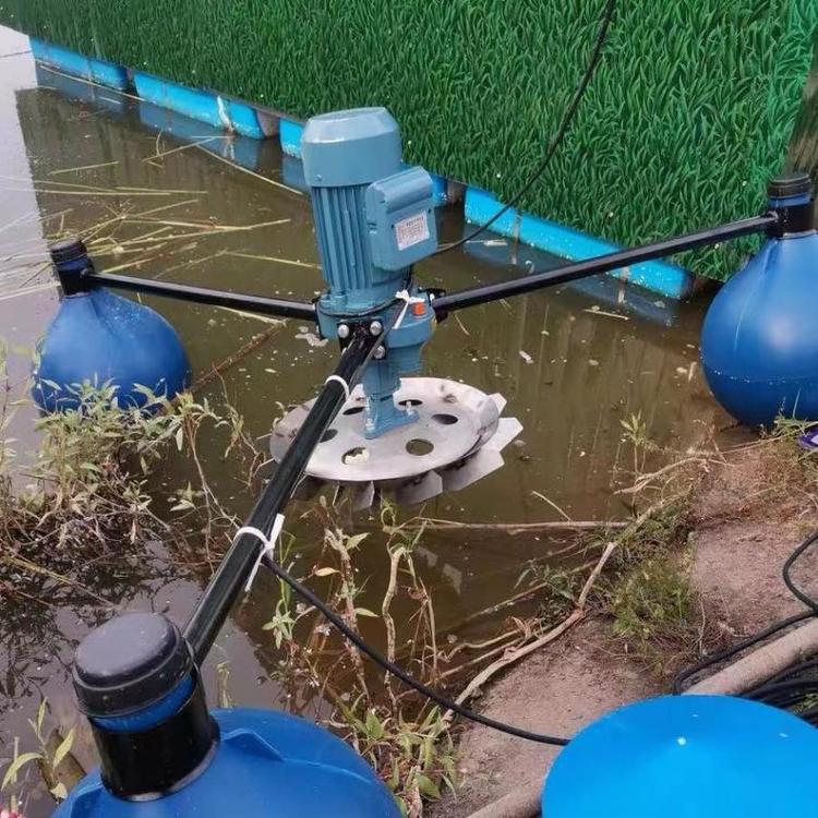 图片说明:一个标准化的大闸蟹养殖池塘,水面布设有多个叶轮式增氧机,正在运行中,水面泛起明显水花,周围可见少量漂浮的水草。增氧机安装位置均匀分布于池塘中央和边缘区域,用于提升全池溶氧水平 大闸蟹养殖池塘增氧设备运行实景图