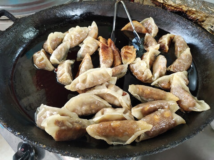 煎锅中正在煎制的莴苣饺子，底部呈现金黄色脆皮