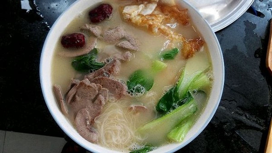 一碗热气腾腾的姜汤面,汤色清澈,姜片浮于汤中,面条整齐排列,旁边配有青菜和鸡蛋 姜汤面成品图