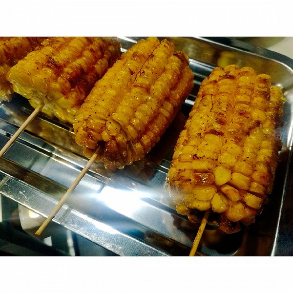 一家人围坐在庭院中享受美食,其中一名儿童正开心地啃食一根烤水果玉米,氛围温馨,体现水果玉米作为健康零食的家庭适用性 一家人正在户外烧烤,桌上摆放着烤熟的水果玉米,金黄诱人的色泽吸引目光,旁边有蔬菜沙拉和饮料,展现健康生活方式场景