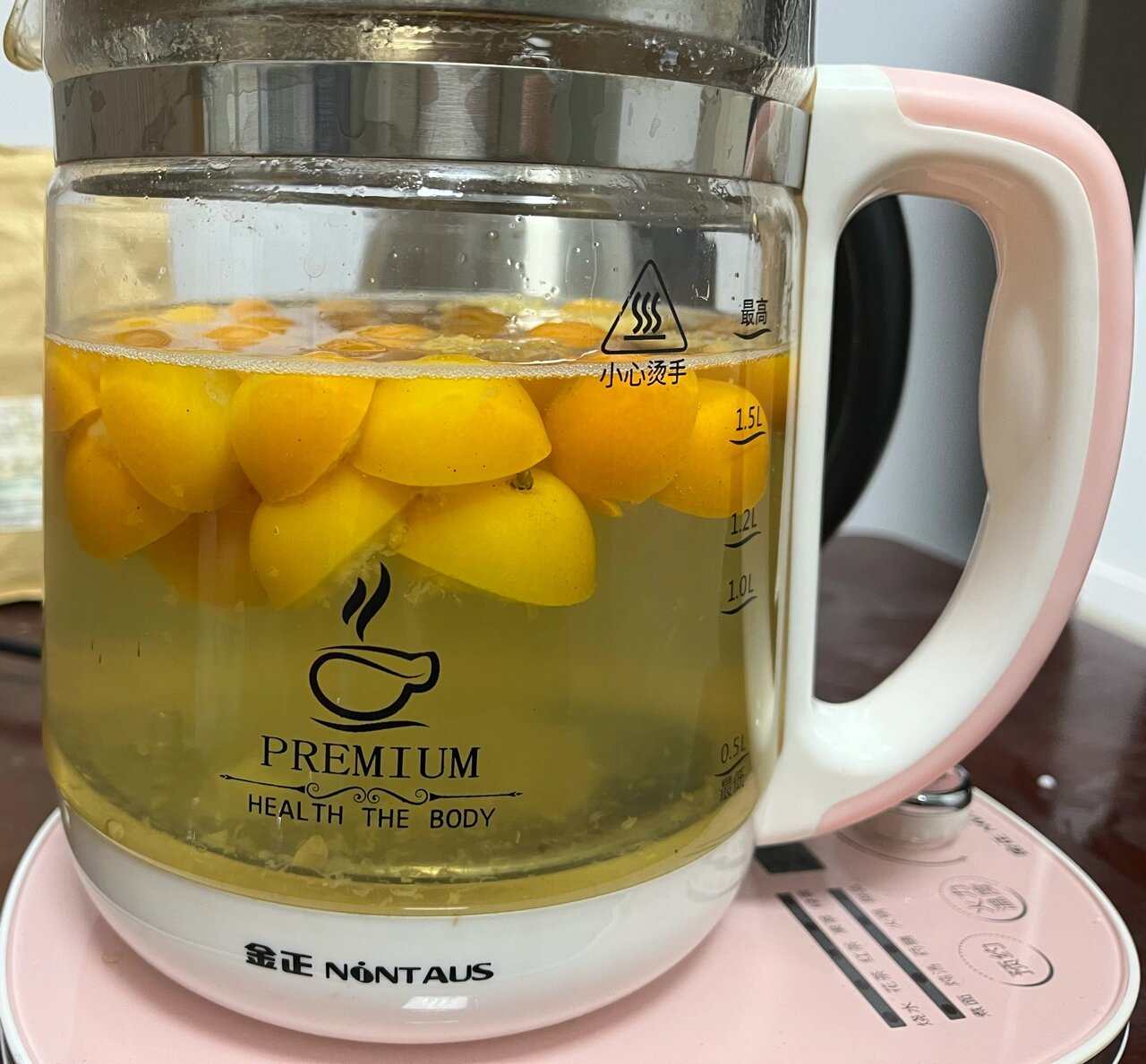 透明玻璃壶中正在冲泡的大麦柠檬茶,可见底部沉淀的炒大麦颗粒与漂浮的黄色柠檬薄片,旁边配有计时器显示‘8分钟’,桌面铺有手写食谱卡片,标题为‘大麦柠檬水制作指南’ 大麦柠檬茶冲泡过程图解