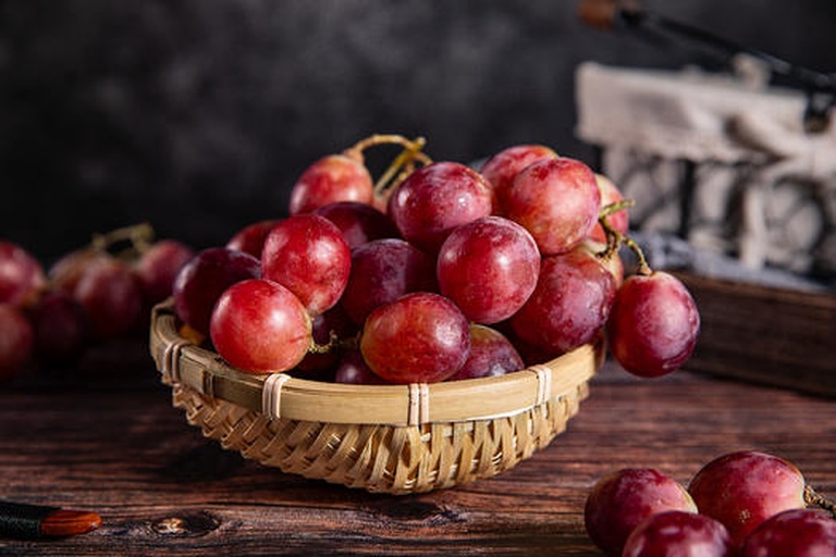 一瓶手工标签的深红色克伦生葡萄酒置于木质餐桌上,旁边有高脚杯盛满酒液,背景为黄昏庭院,氛围温馨优雅 自酿克伦生葡萄酒成品展示