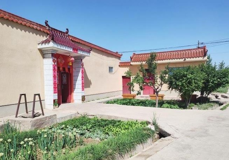 广角镜头拍摄的中国农村院落,多根竹竿横架在庭院之间,上面整齐悬挂着成排的淡绿色条状贡菜,正在阳光下自然晾晒。地面铺有草席,一位老年农妇正整理菜条,背景可见瓦房屋檐和远处田野,体现传统农耕生活气息 传统晾晒贡菜的农村场景