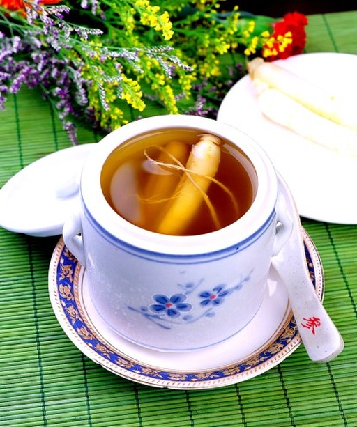 一碗刚出锅的沙参鸡汤特写,汤色呈琥珀金黄,表面浮着几点油花,碗中有鸡腿块、红枣、枸杞和几段北沙参,旁边配有瓷勺,背景虚化显示餐桌环境,突出美食诱人的视觉效果 图片描述
