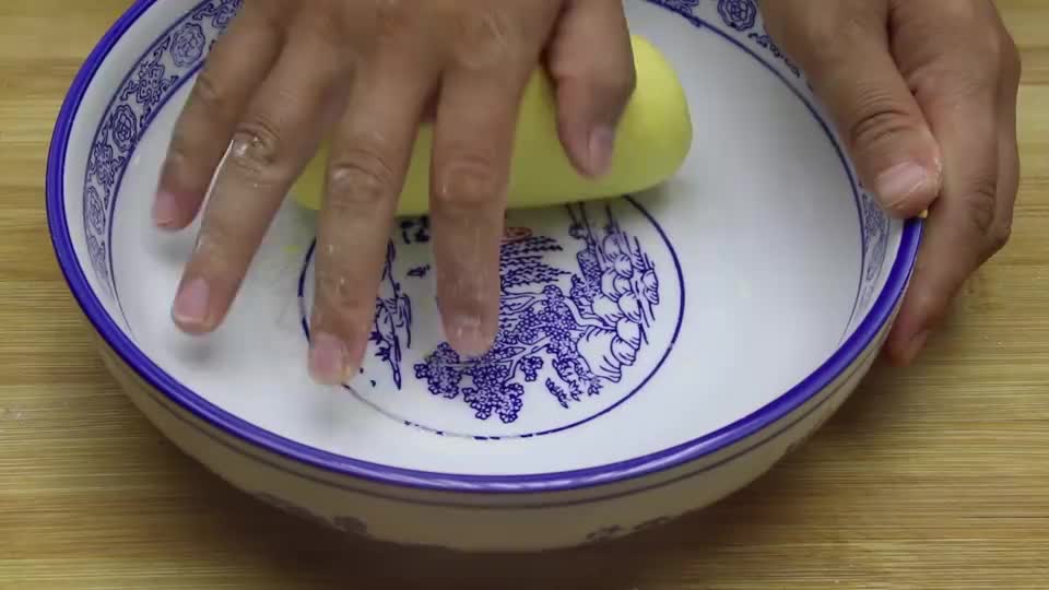 一位厨师正在白色操作台上揉制金黄色的胡萝卜面团,面团光滑有弹性,旁边摆放着碗装胡萝卜泥和面粉,背景为中式厨房 胡萝卜面团揉制过程