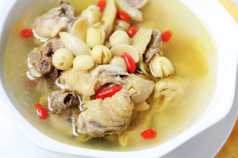 一锅热气腾腾的莲子炖鸡汤,汤色清澈,鸡肉与莲子分明,旁边摆放着葱花点缀 莲子炖鸡成品图