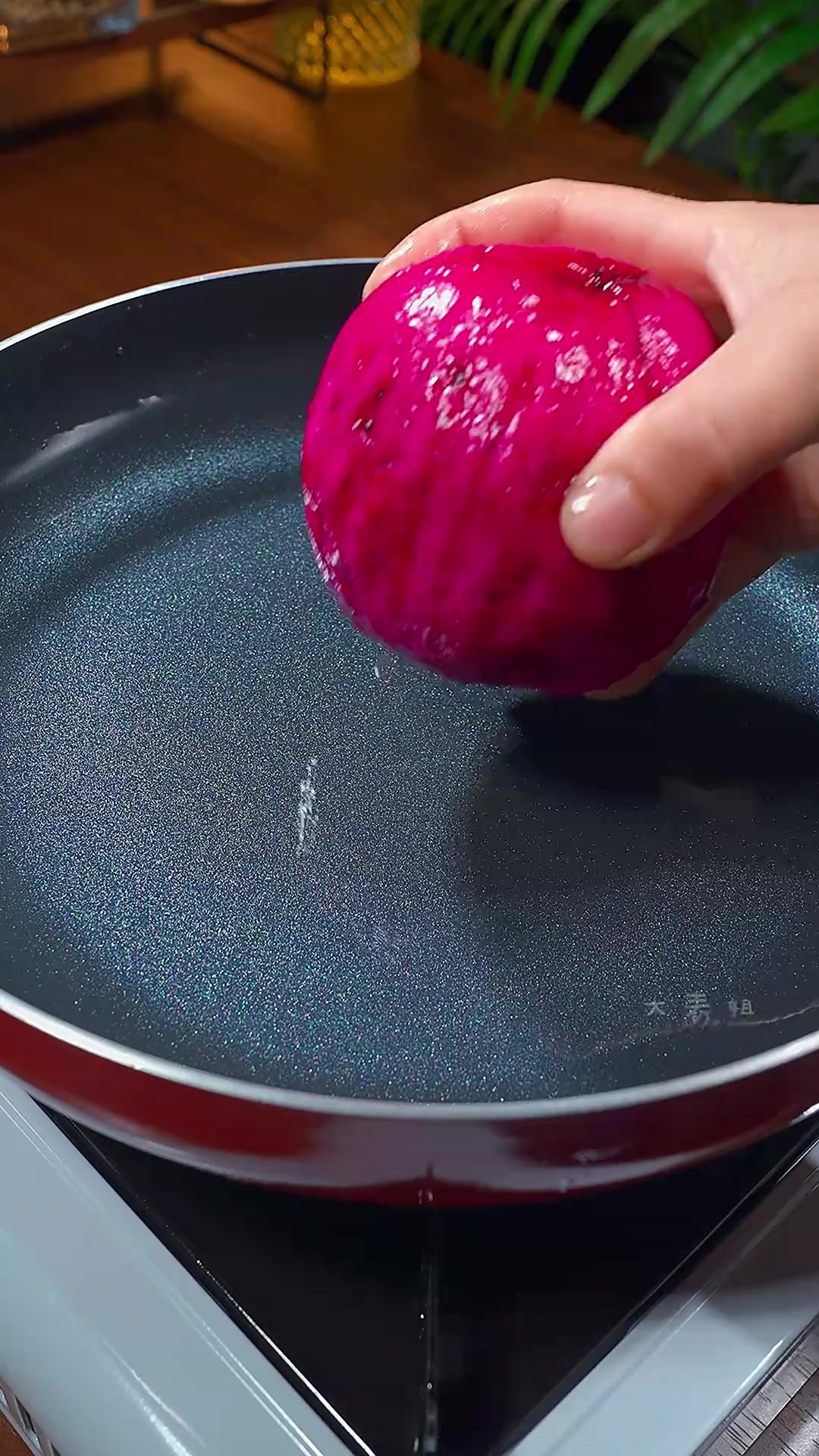 一只手正在用食指轻压火龙果中部,展示检测果实质地的动作。火龙果放置在白色陶瓷盘上,背景为厨房台面,光线柔和明亮,突出操作细节 火龙果触感演示图