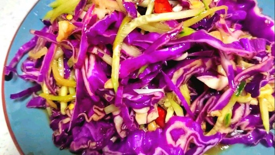 一盘色彩鲜艳的凉拌紫甘蓝,紫红色的菜丝整齐排列,表面淋有少量红油和芝麻点缀,旁边配有蒜末和柠檬片,整体摆盘清新自然,适合夏季冷盘主题 凉拌紫甘蓝特写