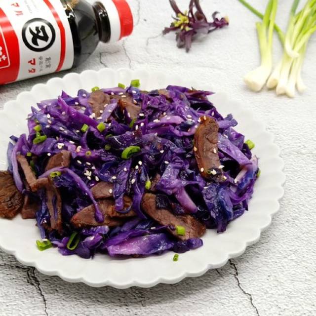 高清俯拍:青花瓷圆盘中盛放刚出锅的紫甘蓝炒牛肉——紫甘蓝丝呈鲜亮紫红色、根根挺立不软塌;牛肉条油润棕亮、纹理清晰;表面可见细微酱汁反光,撒有少许白芝麻与葱花点缀;背景虚化,突出食物质感与色彩对比 紫甘蓝炒牛肉成品特写