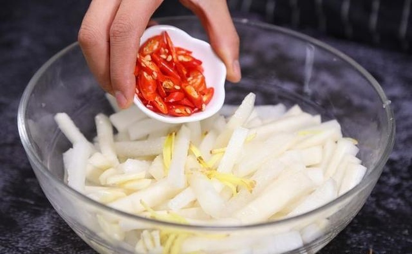 家庭厨房中正在制作青萝卜凉拌菜的场景