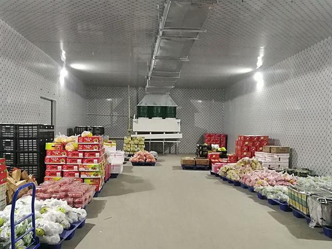展示一个现代化果蔬贮藏车间内部场景:左侧为低温预冷库(标注16℃),中间为恒温后熟区(标注22℃),右侧为包装区。配有温湿度监控仪、通风扇、周转箱堆叠规范标识及工作人员正在检测甜瓜糖度 甜瓜后熟环境控制示意图