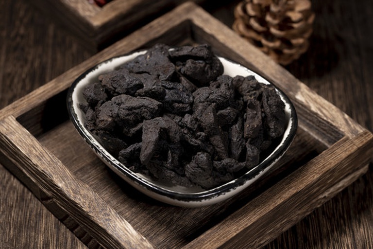 一个现代中式厨房台面上,左侧玻璃罐装着黑色的黑豆,标签写着‘黑豆’;右侧陶瓷碗中放置浅黄色的麦冬药材,标签为‘麦冬’,中间摆放一块木牌写有‘分开使用更安全’字样,背景为柔和灯光下的炖锅 家庭厨房中的食材分开放置场景