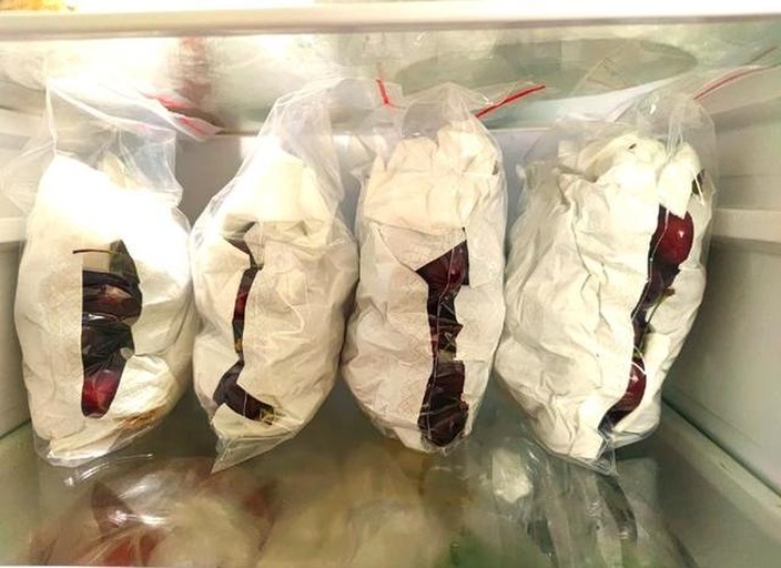 展示如何将美早樱桃放入保鲜盒并冷藏保存,配有厨房纸巾和密封盖 美早樱桃保鲜方法展示图