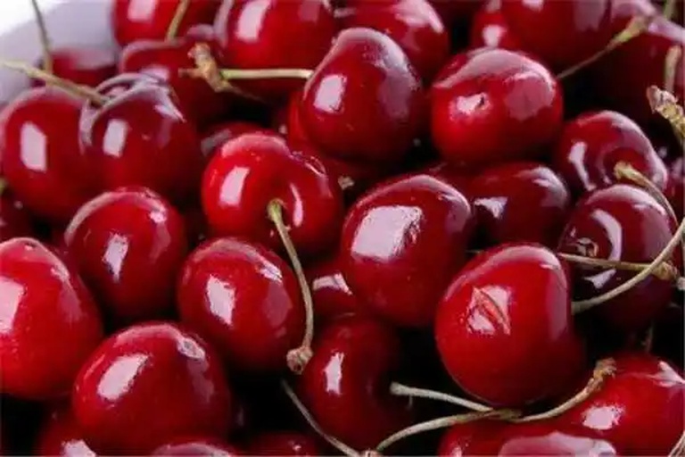 高清车厘子特写照片,展示红色果实和绿色果蒂,背景为自然光线 车厘子特写照片