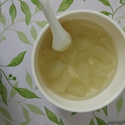 白色瓷碗中盛满晶莹剔透的银耳炖香梨,汤体呈现轻微胶质感,银耳呈半透明状均匀分布,香梨块洁白饱满,表面点缀几粒红色枸杞,背景虚化,灯光温暖,突出食物诱人的质感 成品银耳炖香梨特写图