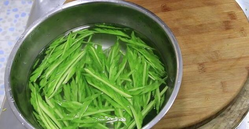 厨房台面上摆放着泡发前的干黄花菜、两个带泥的土豆、一块五花肉、生姜和葱段,旁边放着量勺和刀具,背景为木质砧板 图片描述