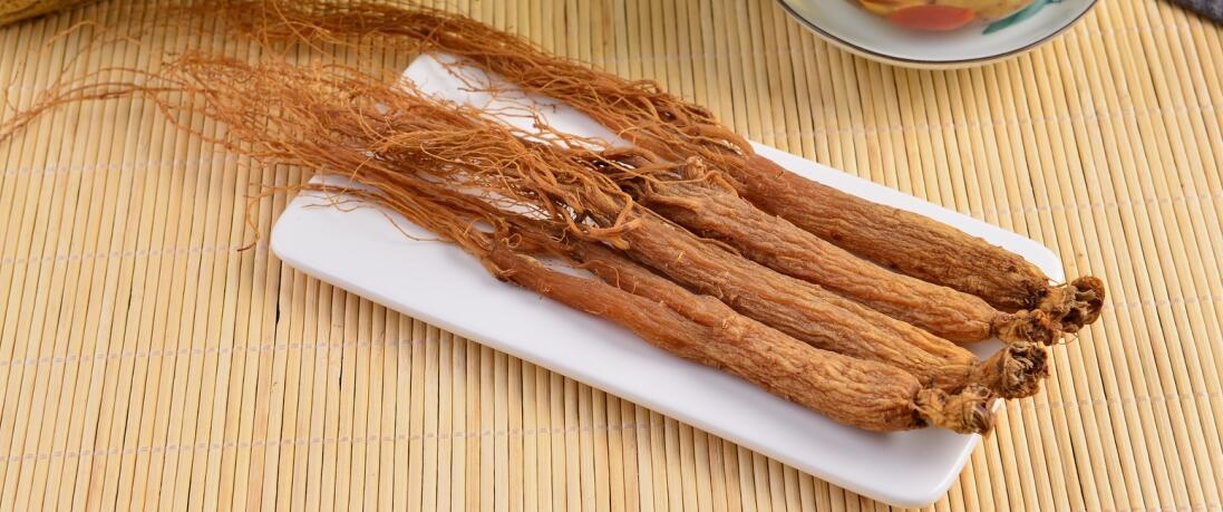 中医师手持电子血压计为老年患者测量血压，背景为中药柜与鲜人参标本瓶