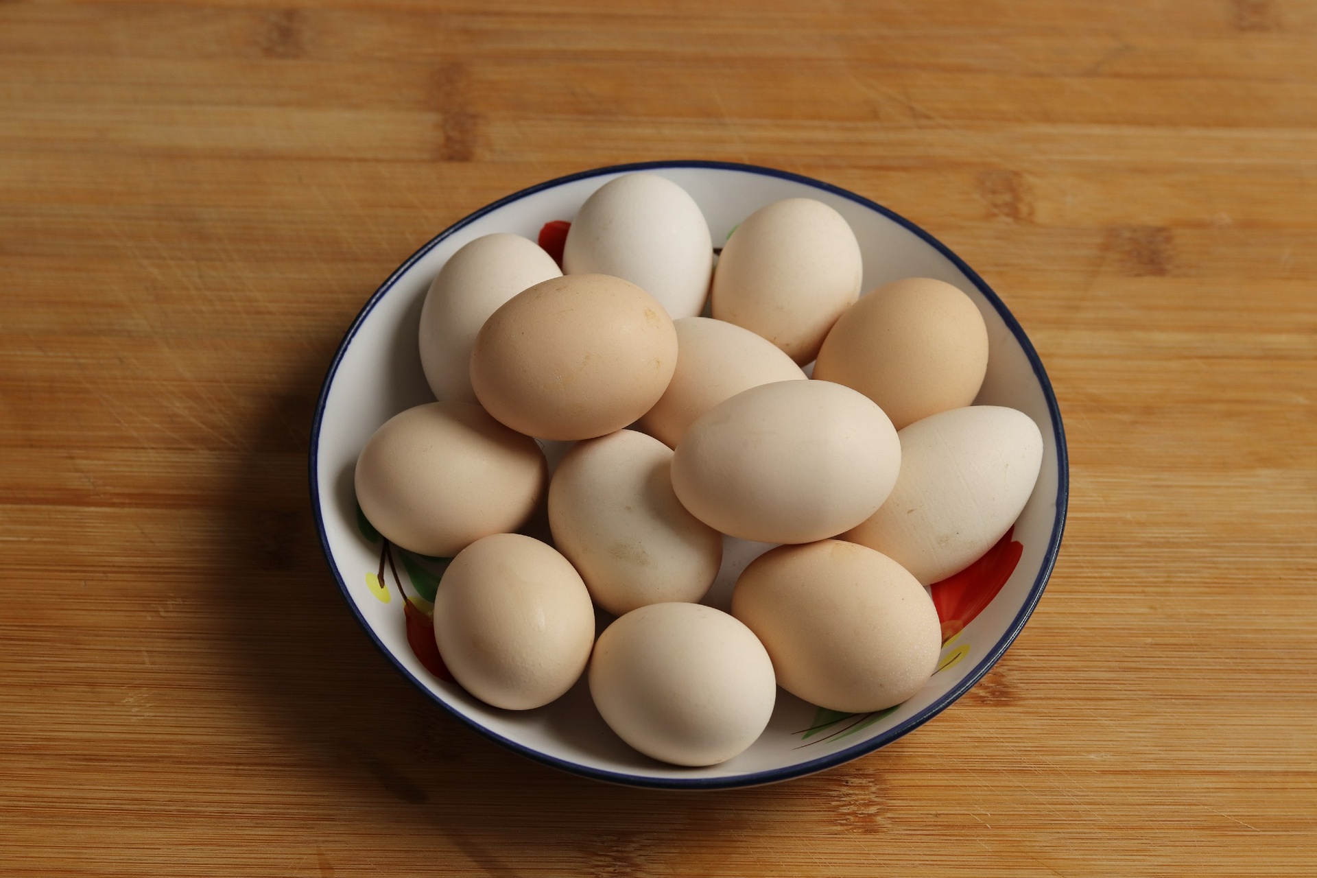 鸡蛋堆放在竹篮中，背景为农村厨房木质台面，光线柔和，体现冬季居家储存场景