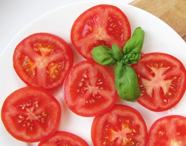 一张美食静物图,展示切开的普罗旺斯番茄与新鲜罗勒、橄榄油和法棍面包搭配的精致摆盘 普罗旺斯番茄与香草、橄榄油搭配的美食摆拍