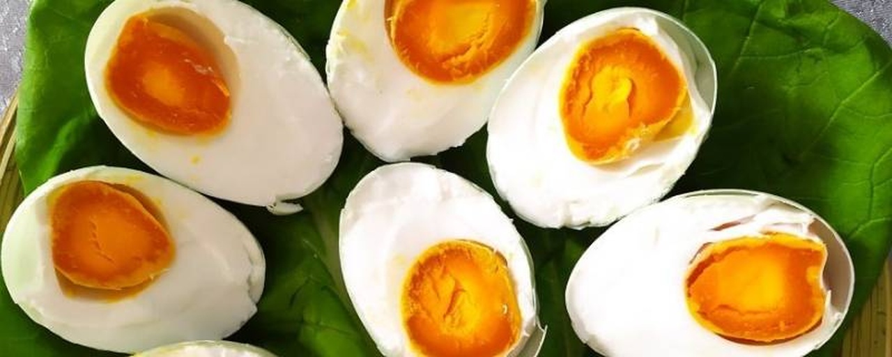 一颗切开的熟咸鸡蛋特写,蛋清洁白,蛋黄呈深橘红色,表面渗出晶莹油珠,背景虚化,突出食物质感与色彩对比 咸鸡蛋切面特写