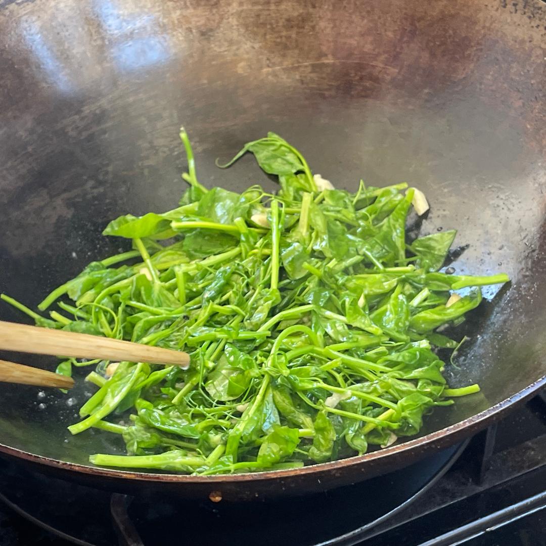 家庭厨房中正在清炒娃娃菜的场景