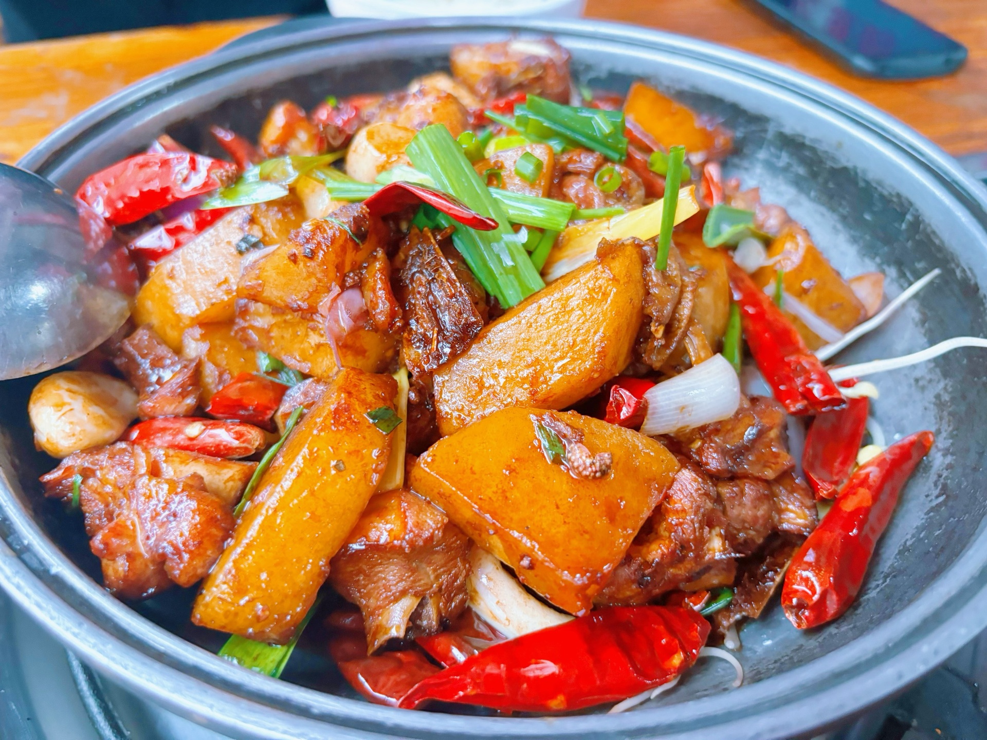 动态抓拍:中大火下鸡肉丁与土豆块在油亮酱汁中翻腾,土豆边缘呈琥珀色焦边,鸡肉表面裹着透亮芡汁,葱蒜配料清晰可见,展现‘镬气’十足的黄金火候状态 鸡肉土豆旺火爆炒过程特写