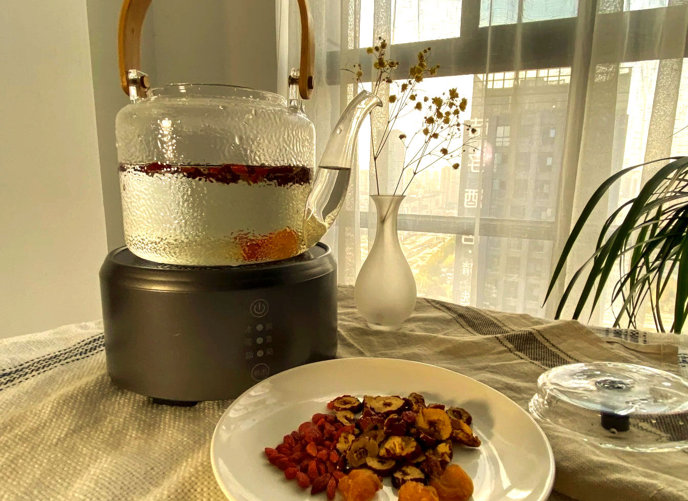 玻璃茶壶中装有红枣片、枸杞、桂圆等搭配食材,热水冲泡,背景为厨房台面,光线柔和温暖 红枣搭配茶饮图