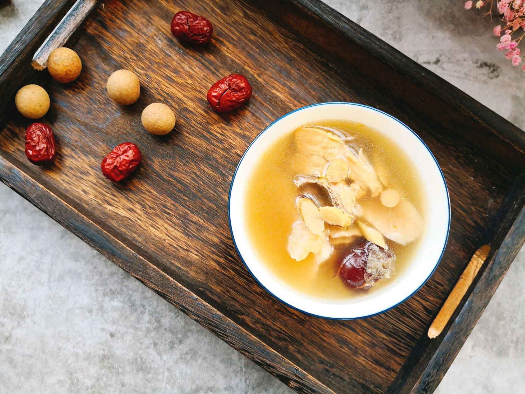 厨房台面上摆放着已处理好的食材:左侧为切块的粉葛浸泡在清水中,中间是一盘焯过水的乌鸡块,右侧是生姜片、去核红枣、枸杞和一小块泡软的陈皮,背景为木质砧板和不锈钢汤锅 粉葛乌鸡汤食材准备