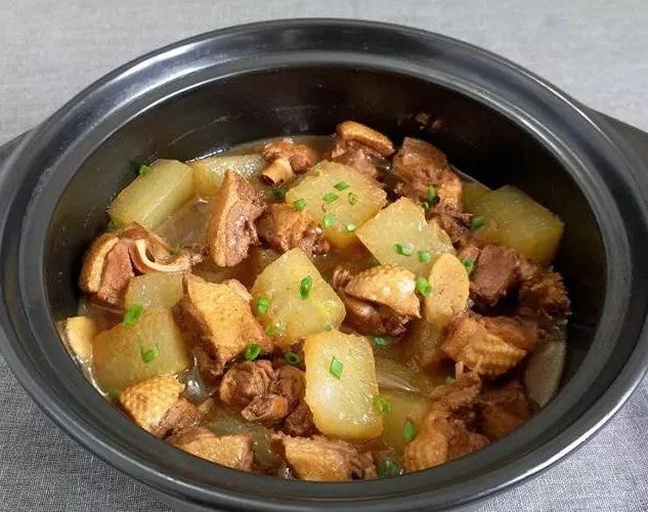 一口砂锅正在炉灶上慢炖,锅盖微启,冒出缕缕蒸汽,锅内可见白色冬瓜块与肉块共煮,汤色清亮微黄,旁边摆放着切好的冬瓜块、姜片和调料碗,展现完整烹饪场景 炖汤过程图