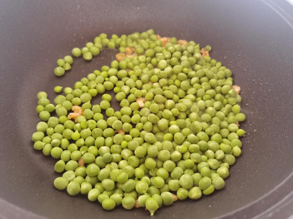 中式炒锅中正在翻炒青豌豆与玉米粒,锅内食材呈现金黄与翠绿交织状态,蒜末清晰可见,灶火旺盛,体现‘锅气十足’的烹饪场景 青豌豆炒玉米烹饪过程图