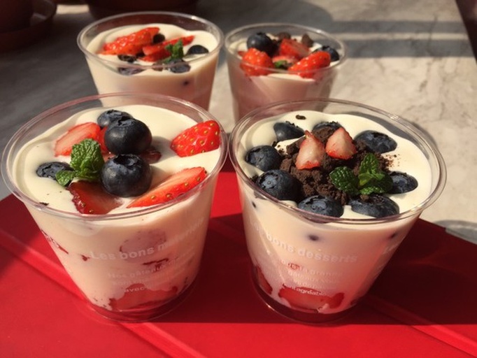 芝士奶油草莓分层杯成品图,展示色彩对比与透明容器美感 一组精致的玻璃甜品杯,分层可见红白相间的草莓果粒与芝士奶油,顶部点缀薄荷叶,摆放于木质餐盘上