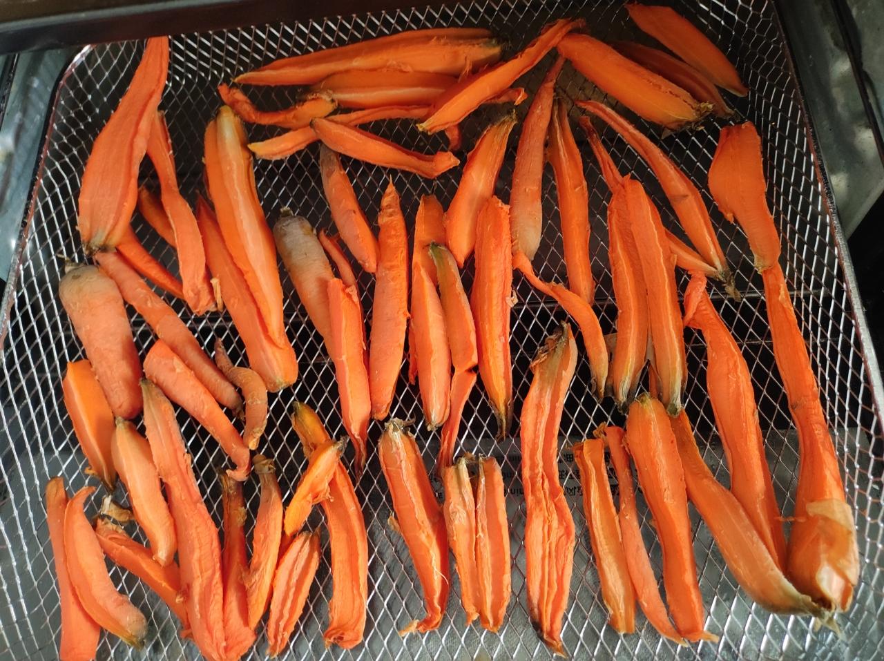 烤盘中铺满焦糖色胡萝卜块与紫洋葱块,表面油润反光,边缘呈深褐色脆边,撒着墨绿色迷迭香碎和粗粒海盐,背景为不锈钢烤箱内壁 烤胡萝卜洋葱特写