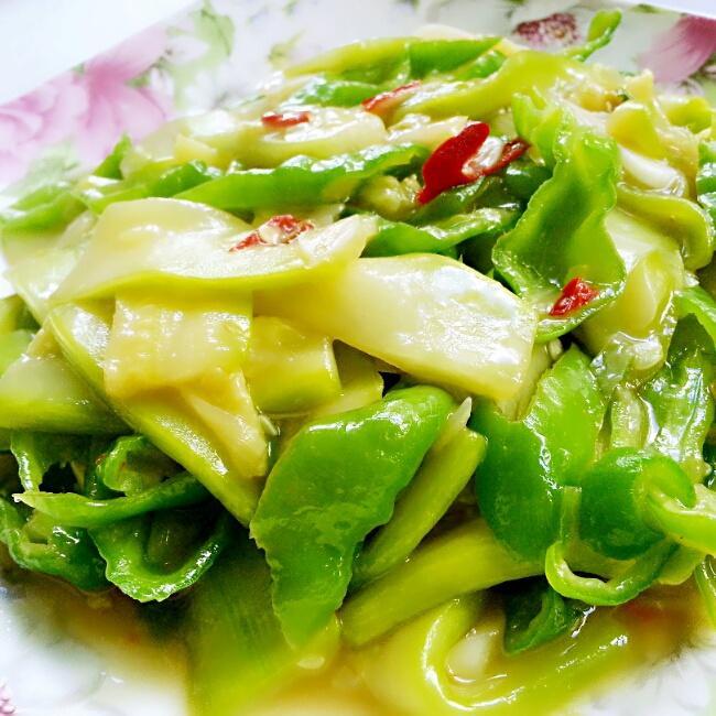 厨房场景中红椒与大青椒的不同烹饪应用：左侧玻璃碗盛放切丝的大青椒沙拉（配柠檬汁、紫洋葱），右侧不粘锅中红椒条与虾仁、橄榄油同炒，锅气升腾