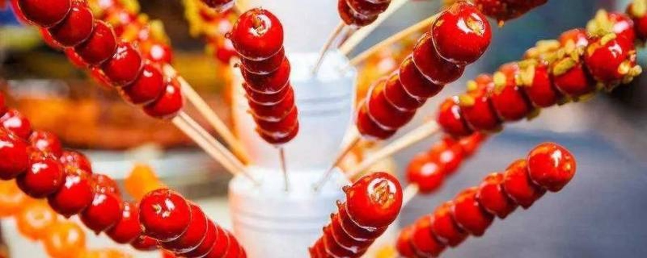 成品展示:数串金桔冰糖葫芦整齐排列于红色托盘中,糖壳光亮如琉璃,映射自然光线,营造温暖节日气氛 成品金桔冰糖葫芦摆盘图,糖衣晶莹剔透,在阳光下闪耀光泽,背景为节日氛围布置