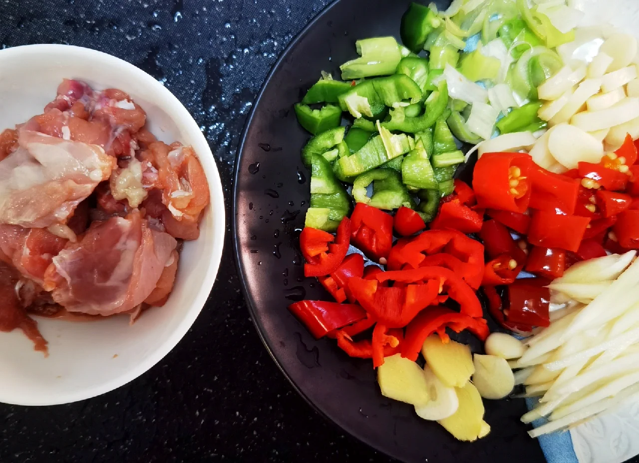 整齐摆放的鸡块、花椒、大葱段、干辣椒等食材,准备开始烹饪 食材处理图