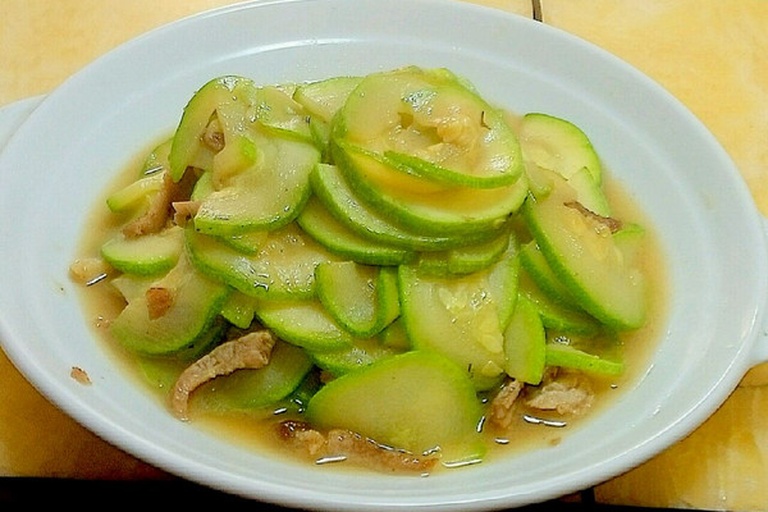 一个现代家庭厨房内景,不锈钢锅中正在炖煮节瓜排骨汤,汤色乳白,节瓜切成块状漂浮其中,旁边放有生姜片和枸杞,灶台整洁,体现节瓜作为家常养生食材的日常应用场景 家庭厨房中正在用节瓜炖汤的场景
