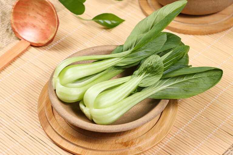 厨房操作台上摆放着新鲜的白色鲜平菇和翠绿的小白菜,平菇被撕成条状,青菜切成段,茎叶分离置于白色瓷盘中,背景为木质砧板和不锈钢刀具,自然光线照射,突出食材的新鲜质感 鲜平菇与青菜的原材料展示