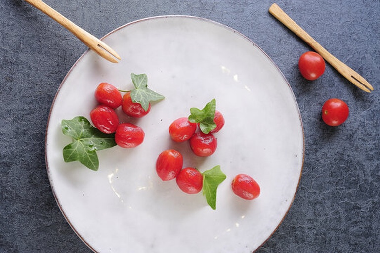 一盘新鲜采摘的红色圣女果与翠绿色水果型小黄瓜并排摆放在木质砧板上,背景为自然光厨房环境,果实表面带有细微水珠,展现新鲜状态 圣女果与水果型小黄瓜并列摆放的高清特写