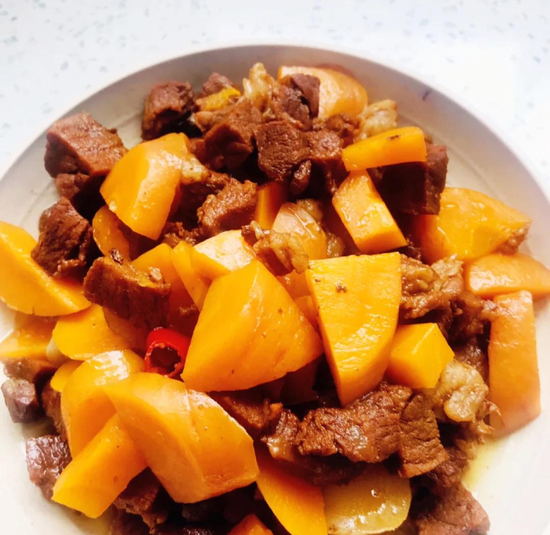 白色瓷碗中盛有牛肉炖南瓜,牛肉块色泽红润,南瓜金黄软糯,汤汁浓稠,表面撒有少许葱花点缀,整体呈现温暖诱人的家常风味 成品牛肉炖南瓜特写